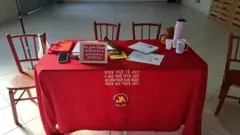 Mesa de um grupo dos Jogadores Anônimos em Novo Hamburgo, no Rio Grande do Sul, coberta com uma toalha vermelha, com um quadro sobre a mesa onde se lê: "Só por hoje evitarei a primeira aposta"