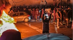 Tahran caddesinde y&uuml;z kadar kişi fotoğrafta kadrajda. Alev alev yanan bir lastik ve bir kişi bir poster kaldırıyor. 