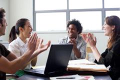 Grupo de pessoas em escritório aplaudindo e comemorando