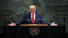 Trump em discurso na Assembleia Geral da ONU. Ele usa terno e fala em um microfone