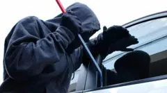 Voleur essayant d'ouvrir la portière d'une voiture.