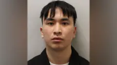Police mugshot of Zou, looking impassively at di camera