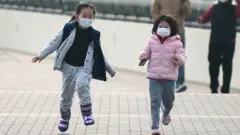 two little girls running wearing masks