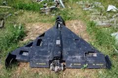 Un dron de color negro con escritura en ruso en las alas, yace derribado sobre césped.