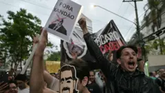 Manifestantes seguram um cartaz pedindo "fora Xandão" e uma faixa com os dizeres "Vorcaro na cadeia".