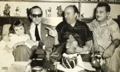 Três homens e uma criança sentados em sofá, sorrindo