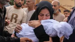 أم تحتضن رضيعها ذا الثمانية أشهر الذي قتل في غارات إسرائيلية على مدينة خان يونس بقطاع غزة في 28 أكتوبر/تشرين الأول