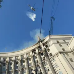 Строительство правительства Украины, над крышей, в небе, в небе вертолет, который принимает участие в погашении пожара, виден в небе.