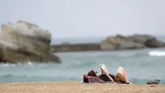 women reading a book in the beach