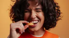 Жінка посміхається і кусає дольку мандаринки