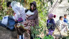 11 Mart 2025'te Suriye'nin batı kıyı şeridi ile kuzey Lübnan arasındaki sınırı oluşturan Hekr al-Daher bölgesindeki Nahr al-Kebir nehrini geçen siviller.