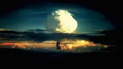 Una nube en forma de hongo blanca ondulante, moteada de naranja, atraviesa una capa de nubes durante la Operación Ivy, la primera prueba de una bomba de hidrógeno, en el atolón Enewetak en las Islas Marshall.