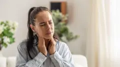 Tiroid bezlerini tutan bir kadın