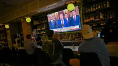 Pessoas veem o pronunciamento de Trump pela TV em Chicago, nos EUA