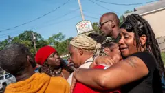 Toplam altı kişi birbirini teselli etmeye çalışıyor. Kadınlardan ikisi birbirlerine sarılmış durumda.