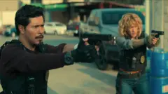 Cena da série em que um homem e uma mulher apontam duas armas para alguém