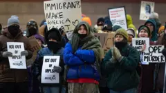 Un grupo de personas muy abrigadas contra el frío participan en Mineápolis en una protesta contra ICE.