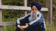 Seorang pria berjenggot tebal dengan sorban sedang duduk dan tersenyum.