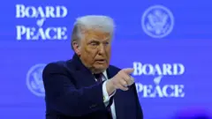 Donald Trump apontando para a plateia, sobre um fundo azul alusivo ao Conselho de Paz criado por ele