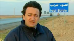 Fergal Keane em frente a uma placa indicando a fronteira com o Iraque