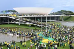 Una multitud de personas aglomeradas en torno a la Esplanada de los Ministerios en Brasilia. Algunos portan una bandera enorme de Brasil.