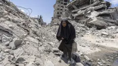 Seorang perempuan berupaya mengambil paket bantuan yang dijatuhkan dari pesawat di Kota Gaza, 7 Agustus 2025.