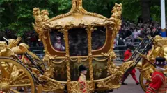 Queen's hologram in Gold State Coach,