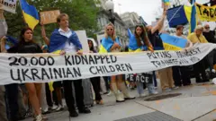 Pessoas com a bandeira amarela e azul da Ucrânia carregam cartazes contra a guerra no país.