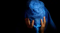 stock image of woman in burka with head in hands