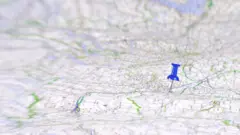 Marcador azul fincado sobre um mapa de papel