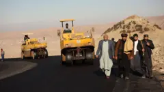 مردان در حال بازدید از قیرریزی جاده 