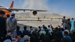 Afghan people sit as they wait to leave the Kabul airport in Kabul on August 16, 2021
