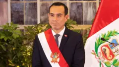 José Jerí con una banda con los colores de la bandera peruana y una bandera en el fondo.