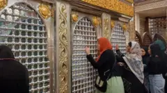 কায়রোর হুসাইনি মসজিদের ভেতরে কয়েকজন নারী হাত দিয়ে লোহার তৈরি প্রাচীর ধরে আছেন