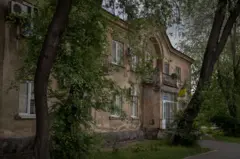El juzgado del distrito de Zavodskyi. Hay árboles frente al edificio que ondea una bandera ucraniana.