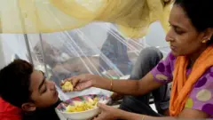 ডেঙ্গু জ্বরে আক্রান্ত শিশুকে খাওয়াচ্ছেন তার মা, ঢাকা, ১৩/০৯/২০১৯