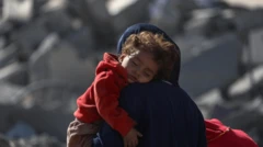 Uma mulher segura uma criança que parece estar dormindo, vestindo um suéter vermelho