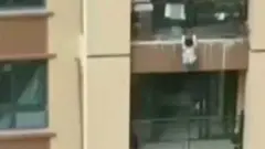 Niño colgado de un balcón.