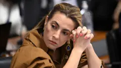 Soraya Thronicke com os dedos entrelaçados apoiando a cabeça.