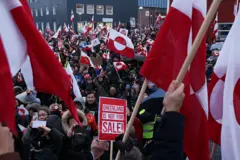 Manifestantes com bandeiras da Groenlândia e um cartaz com os dizeres "a Groenlândia não está à venda", em inglês, durante um protesto contra os planos de Donald Trump na capital groenlandesa, Nuuk