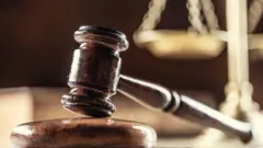 مطرقة القاضي خشبية وفي الخلفية ميزان ذهبي