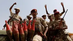 صورة لمسلحين يرتدون زياً عسكرياُ وقبعات حمراء، بينما يجلسون فوق سيارة مدرعة حاملين السلاح.