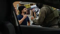 Jovem enfrenta agentes federais americanos, depois que um trabalhador foi preso em casa no Edison Park de Chicago, Illinois, em 31 de outubro de 2025. Os agentes deram duas advertências e o ameaçaram de prisão por interferir na "Operação Midway Blitz" do governo do presidente americano Donald Trump, uma intensificação do controle de imigração em toda a região de Chicago