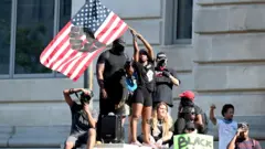 Manifestantes en Washington D.C. con una bandera de EE.UU.