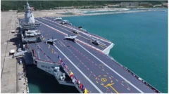 Flight deck of the latest aircraft-carrier of China.  Two fighter aircraft stationed at take-off points. There are also two helicopters. 