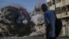 Житель Гази дивиться на будівлю, по якій щойно було нанесено ізраїльський авіаудар