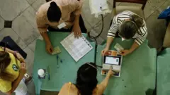 Eleitores e mesários colhendo assinaturas e realizando biometrias