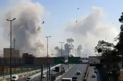 Fumaça ao fundo de estrada em cidade