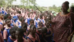 Olukọ obinrin mu ẹgbẹ lọwọ pẹlu awọn akẹkọọ ni iwaju rẹ