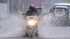 වර්ෂාව මැද ධාවනය කෙරෙන යතුරු පැදියක්